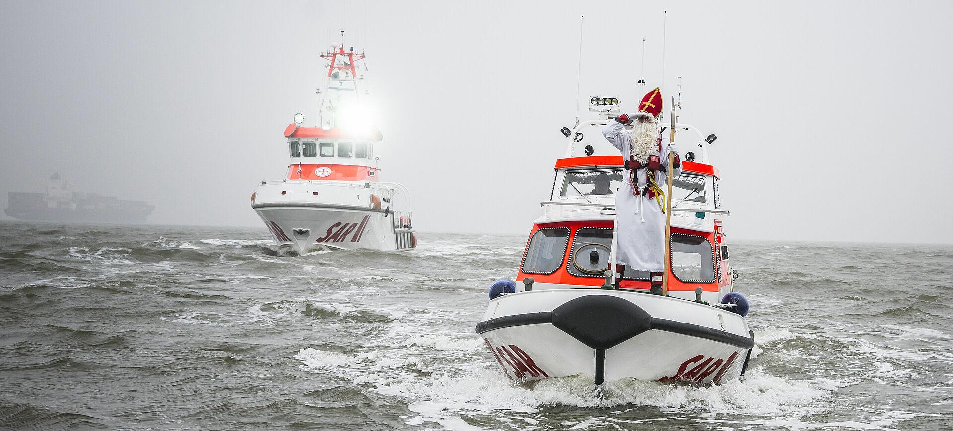 Nikolaus auf einem Tochterboot der DGzRS, im Hintergrund ein Seenotrettungskreuzer