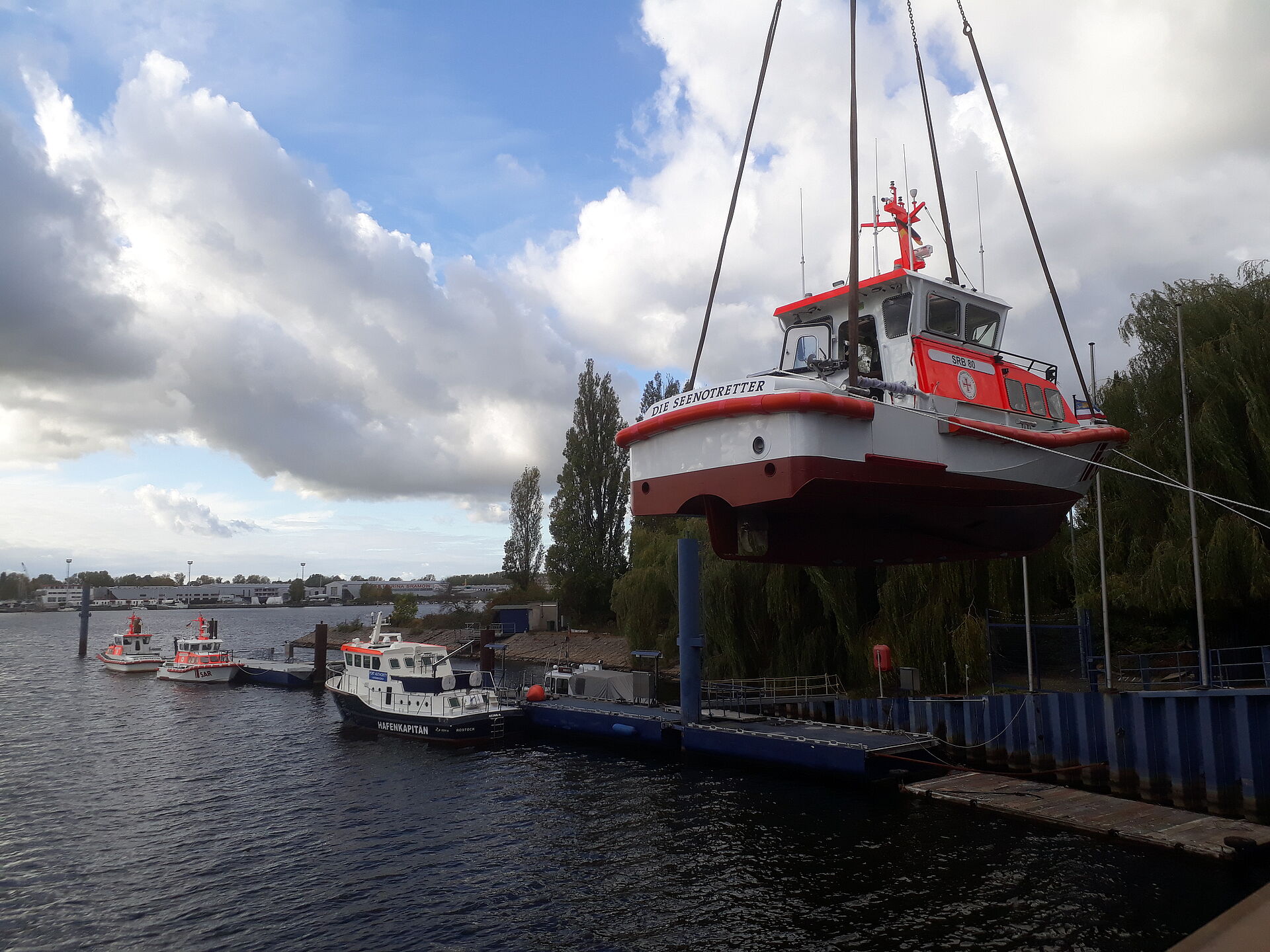 Ein großer Kran hebt das Seenotrettungsboot mit Laschen in das Werftbecken.